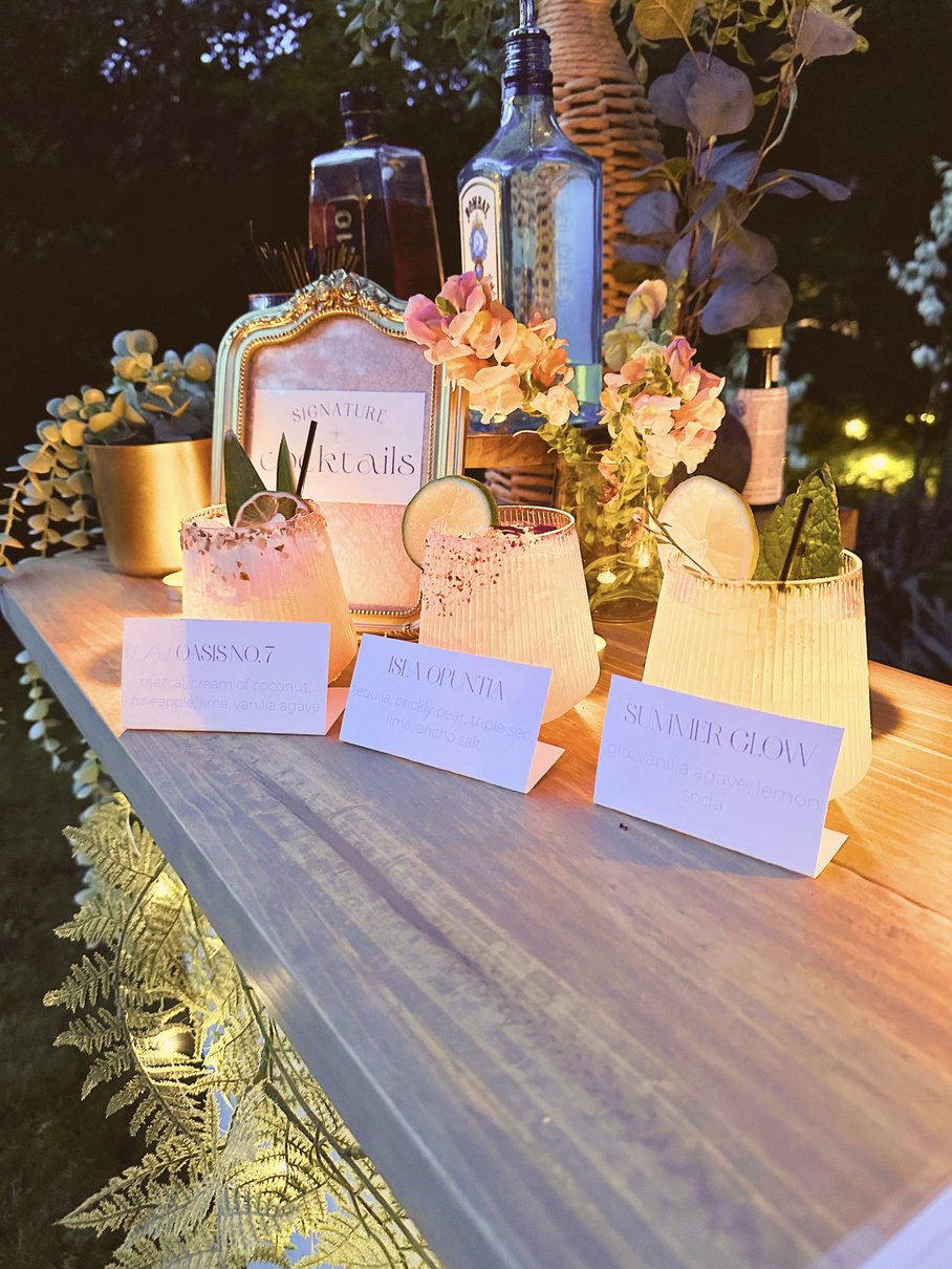 Backlit signature cocktails with printed menu cards on an evening bar